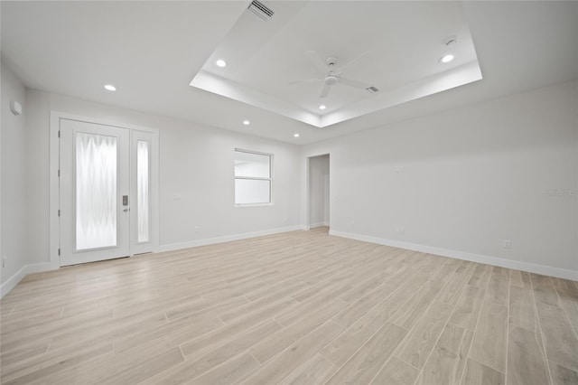 spare room featuring light hardwood / wood-style floors, a raised ceiling, and ceiling fan