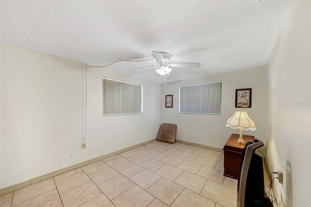 empty room with a textured ceiling, ceiling fan, and light tile patterned flooring