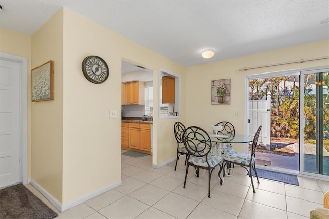 dining space featuring sink, light tile patterned floors, and a textured ceiling