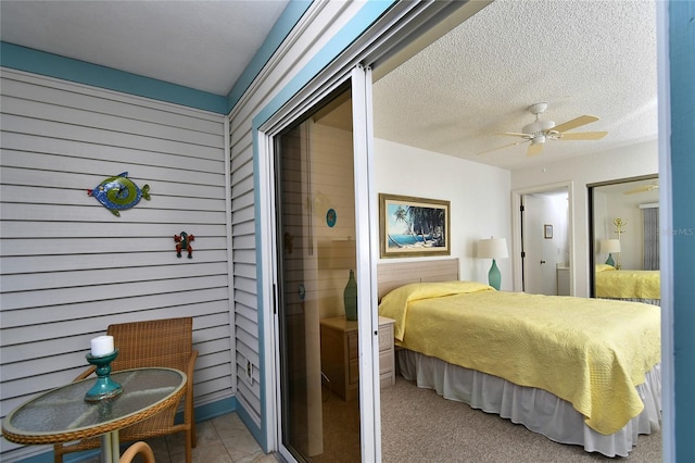 bedroom with ceiling fan, wooden walls, and a textured ceiling