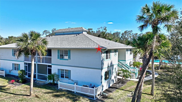 rear view of house featuring a lawn and a balcony