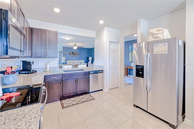 kitchen with sink, ceiling fan, dark brown cabinets, stainless steel appliances, and light stone countertops