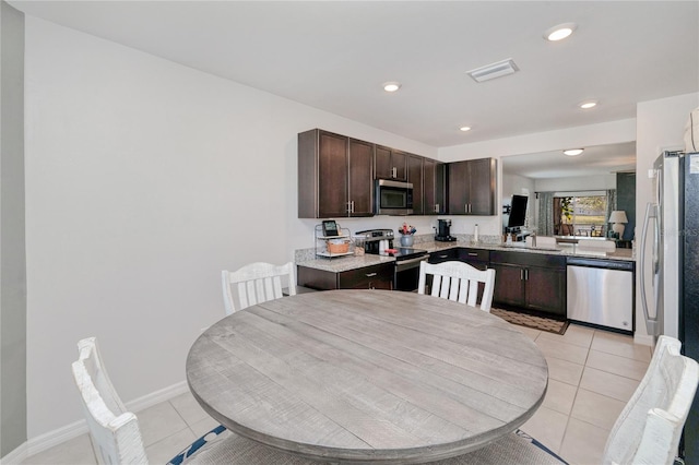 kitchen featuring light tile patterned flooring, dark brown cabinetry, appliances with stainless steel finishes, and sink