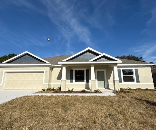 craftsman-style house featuring concrete driveway, an attached garage, a front yard, and stucco siding