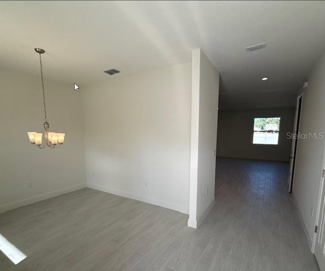 corridor featuring a chandelier, baseboards, and wood finished floors