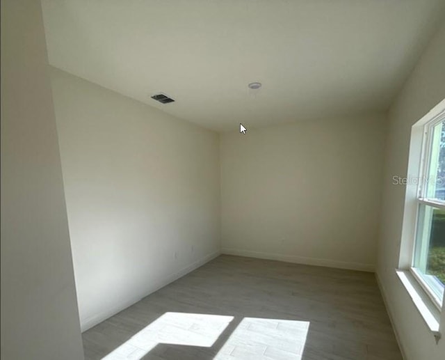 spare room featuring light wood-style floors, visible vents, and baseboards