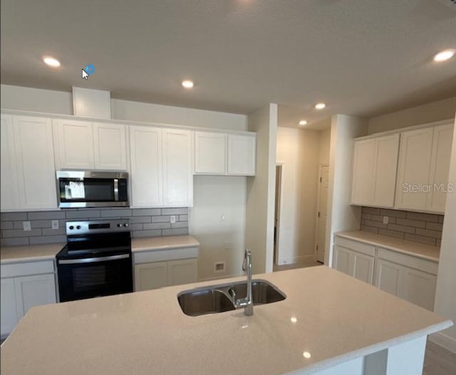 kitchen with a sink, stainless steel microwave, electric range, and white cabinetry