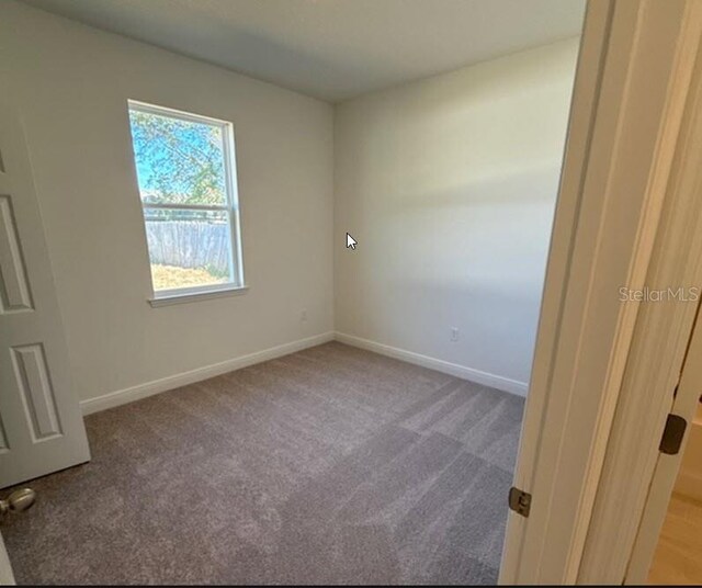 carpeted empty room featuring baseboards