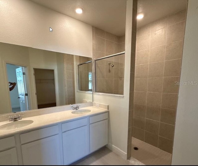 full bath with double vanity, walk in shower, and a sink