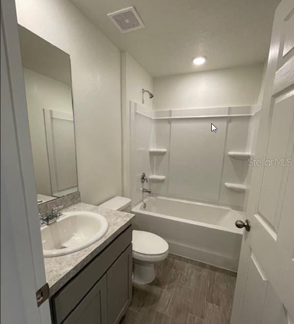 full bathroom featuring vanity, hardwood / wood-style floors, tub / shower combination, and toilet