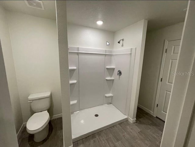 bathroom featuring a shower, wood-type flooring, and toilet