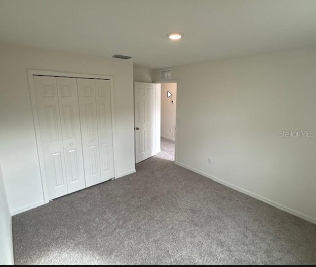 unfurnished bedroom featuring dark carpet and a closet