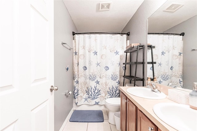 bathroom with tile patterned flooring, vanity, a textured ceiling, and toilet