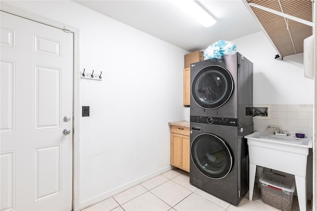 laundry room featuring light tile patterned flooring, cabinets, and stacked washer / drying machine