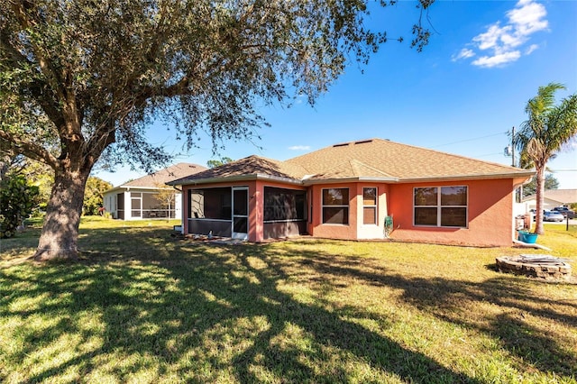 rear view of property with an outdoor fire pit, a yard, and a sunroom