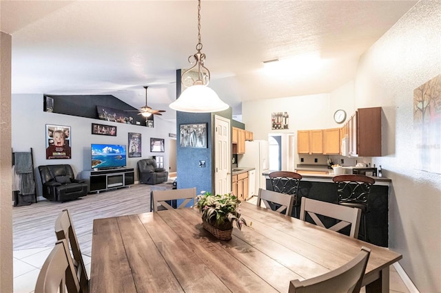 dining area with vaulted ceiling, ceiling fan, and a textured ceiling