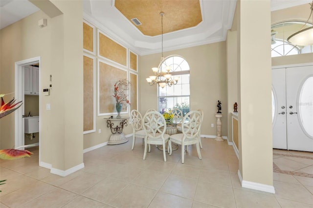 dining space featuring light tile patterned flooring, ornamental molding, a tray ceiling, and a notable chandelier