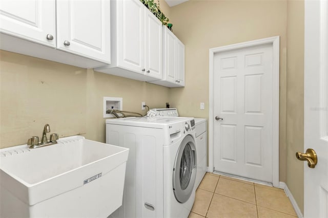 washroom featuring cabinets, washing machine and dryer, sink, and light tile patterned floors