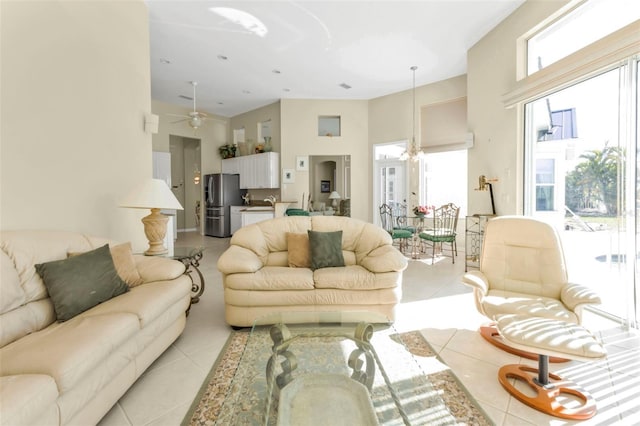 living room featuring light tile patterned flooring, a towering ceiling, and ceiling fan with notable chandelier