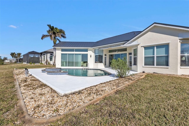 rear view of house with a swimming pool with hot tub, a yard, and a patio area