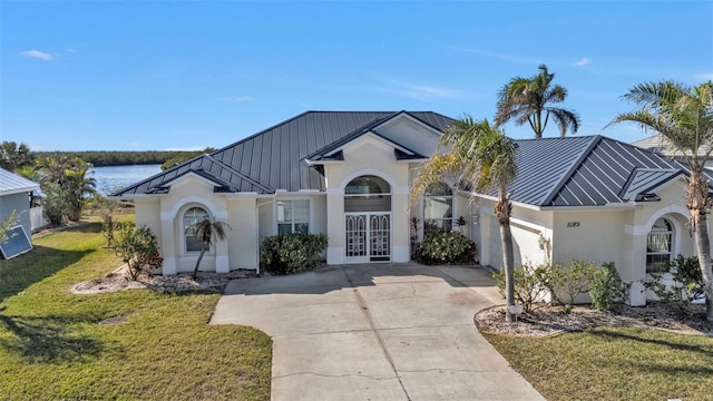 view of front of house featuring a garage, a front yard, french doors, and a water view