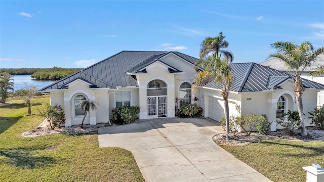 view of front facade with a water view, a garage, a front lawn, and french doors