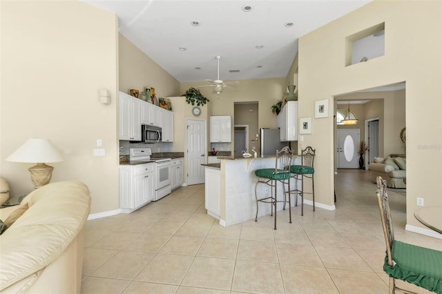 kitchen featuring light tile patterned flooring, appliances with stainless steel finishes, a breakfast bar, white cabinets, and kitchen peninsula