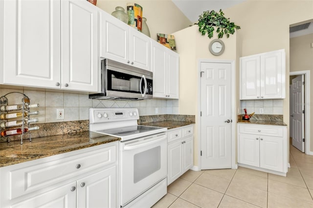 kitchen featuring white electric stove, white cabinetry, light tile patterned floors, and backsplash