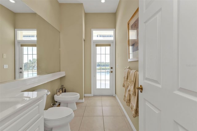 bathroom with tile patterned flooring, toilet, a healthy amount of sunlight, and a bidet