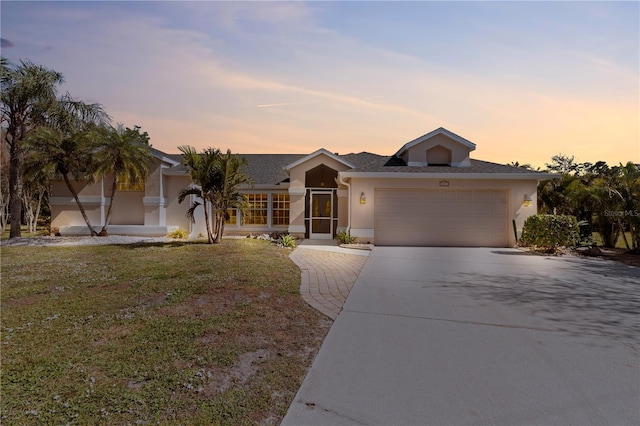 single story home featuring a garage and a lawn