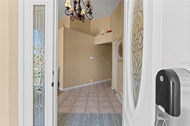 foyer entrance with light tile patterned floors, a notable chandelier, and a textured ceiling