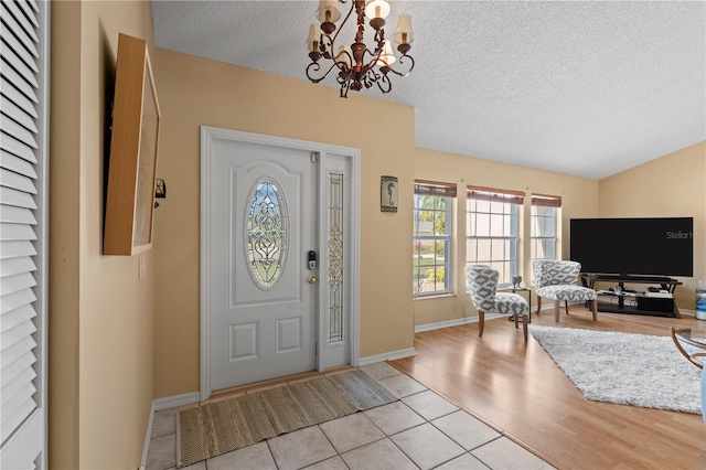 foyer with an inviting chandelier, a textured ceiling, and light hardwood / wood-style flooring