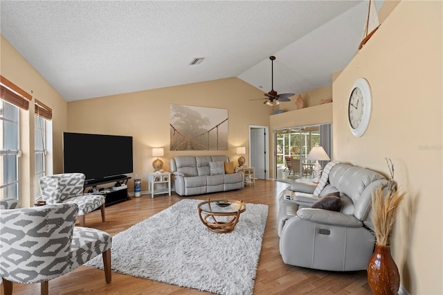 living room featuring ceiling fan, wood-type flooring, a textured ceiling, and vaulted ceiling