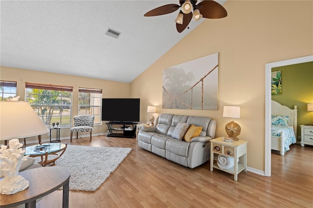 living room with ceiling fan, lofted ceiling, light hardwood / wood-style flooring, and a textured ceiling