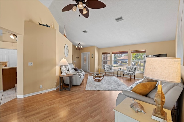 living room with lofted ceiling, hardwood / wood-style flooring, ceiling fan with notable chandelier, and a textured ceiling