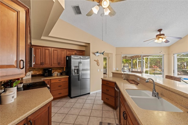 kitchen with appliances with stainless steel finishes, sink, light tile patterned floors, and lofted ceiling