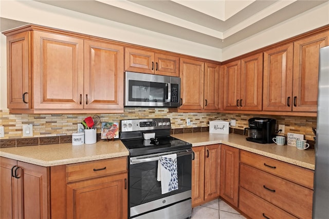 kitchen with light tile patterned flooring, stainless steel appliances, and tasteful backsplash