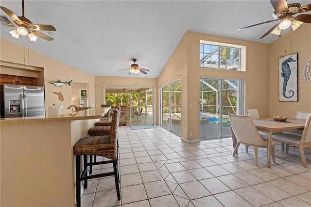 interior space featuring light tile patterned flooring, ceiling fan, lofted ceiling, and a textured ceiling