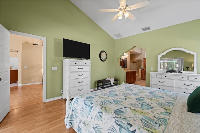 bedroom with ceiling fan, high vaulted ceiling, light wood-type flooring, and ensuite bath