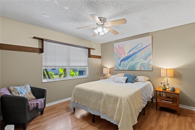 bedroom with ceiling fan, light hardwood / wood-style floors, and a textured ceiling