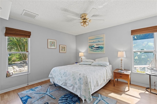 bedroom with multiple windows, light hardwood / wood-style flooring, and ceiling fan