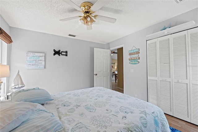 bedroom featuring hardwood / wood-style flooring, ceiling fan, a textured ceiling, and a closet