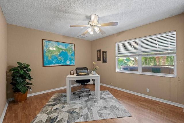 office space with ceiling fan, a textured ceiling, and light wood-type flooring