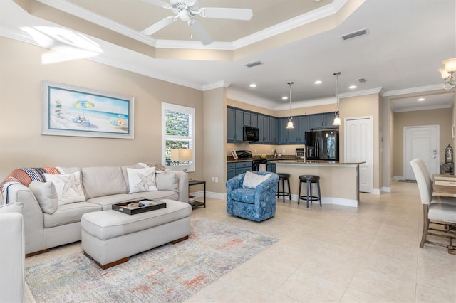 living room with crown molding, ceiling fan, and a tray ceiling