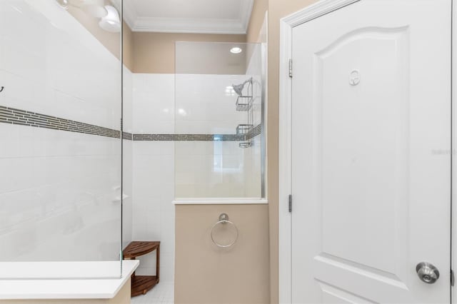 bathroom featuring tile patterned flooring, ornamental molding, and tiled shower