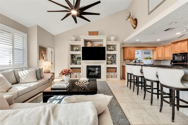 tiled living room featuring ceiling fan and vaulted ceiling