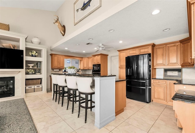 kitchen with light tile patterned floors, ceiling fan, a kitchen breakfast bar, black appliances, and a kitchen island