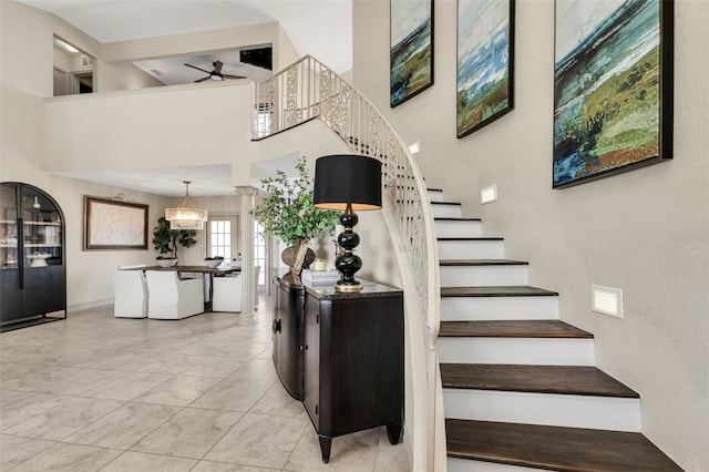 stairway with a high ceiling, tile patterned flooring, and ceiling fan