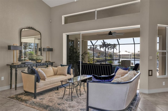 tiled living room with a water view, ceiling fan, and a high ceiling