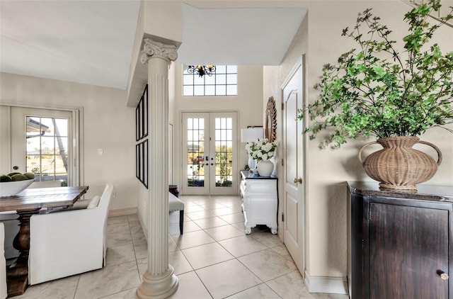 entryway with light tile patterned floors, decorative columns, french doors, and a healthy amount of sunlight